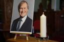 A candle and a photo at a vigil at St Michael & All Angels church in Leigh-on-Sea Essex for Conservative MP Sir David Amess who died after he was stabbed at a constituency surgery.