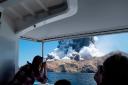 Photo provided by Michael Schade shows tourists on a boat looking at the eruption of the volcano on White Island (Michael Schade/AP)