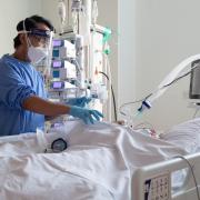 A nurse checks on a patient suffering with Covid-19 on a critical care unit