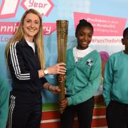 Dame Laura Kenny holds the Olympic torch with schoolchildren from Mossbourne Riverside Academy